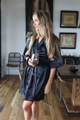 Bata kimono negra de satén elastizado, con mangas al codo, largo por encima de la rodilla y lazo de satén para ajustar en la cintura.