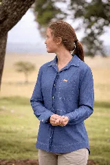 Camisa de algodón liviano color celeste, con manga larga, cuello camisero, bolsillo frontal con parche y etiqueta de marca, y pespuntes en contraste. Cuenta con cierre frontal oculto y botones de madera y coco.