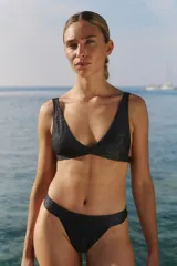 Conjunto de bikini confeccionado en lycra con acabado de lúrex brillante. El corpiño es de diseño triangular con tiras anchas y la bombacha es de corte vedetina con laterales anchos.