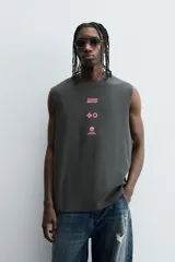 Sudadera sin mangas (tipo chaleco) de color gris oscuro con efecto lavado, corte relajado y cuello redondo. Presenta un estampado frontal en color rosa neón con texto y gráficos abstractos.