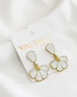 Par de aros colgantes con forma de flor blanca con borde dorado y detalle de gota blanca marmolada en la parte superior.