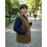 Chaleco de corderito color marrón, de diseño reversible, sin cuello, con cierre de un botón frontal y bolsillos aplicados.