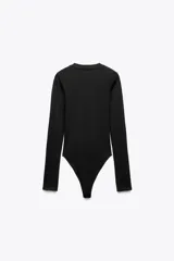 Body de manga larga con cuello redondo, confeccionado en una mezcla de algodón y modal. Presenta cierre inferior con botones a presión.