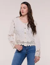 Cardigan corto beige de algodón con bordado en relieve, escote redondo y cierre frontal con botones carey. Mangas largas con detalles de encaje crochet y ruedo con terminación en ondas.