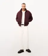 Campera bomber Marfinno para hombre, de gamuza sintética (suede) color tostado, con cuello camisero, cierre frontal metálico, bolsillos frontales y terminaciones en rib en puños y ruedo.