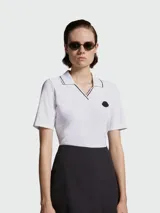 Remera polo de algodón blanca con cuello en V y detalles de líneas finas en contraste. Presenta mangas cortas y el logo de la marca aplicado en el pecho.