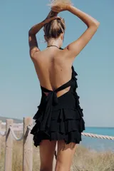 Vestido mini negro de cuello halter y espalda descubierta, con diseño de múltiples volantes en cascada.