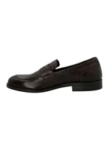 Mocasín estilo penny loafer para hombre, confeccionado en cuero marrón oscuro con textura sutil, punta redonda y suela plana con pequeño tacón.