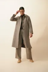 Tapado con cuello solapa y corte recto, color gris. Cierre frontal con botones ocultos, tajos laterales y bolsillos escondidos en corte lateral. Con forro. Tela 100% lana fina sin teñir, diseñada exclusivamente por Don Baez. Hecha 100% en Uruguay.