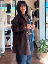 Campera de ecocuero color chocolate, con corte amplio y relajado. Presenta cuello camisero, cierre frontal con botones metálicos y bolsillos frontales de gran tamaño.