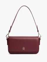 Cartera rectangular de color borgoña con acabado liso y solapa frontal con cierre magnético. Presenta un monograma TH en relieve en la parte delantera. Incluye correa ajustable y extraíble para llevar al hombro o como cartera de mano.