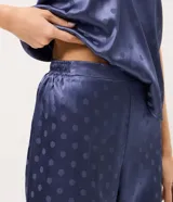 Pijama largo de satén azul con estampa de lunares, compuesto por una musculosa de escote en U con breteles finos y un pantalón de pierna recta con cintura elastizada.