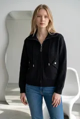 Campera de paño color marrón, con cuello alto, cierre frontal completo y cordones decorativos. Presenta bolsillos frontales con solapa y cierre a presión, y puños tejidos.