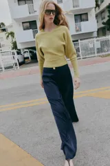 Jersey de punto color verde lima, con cuello pico y manga larga de sisa ancha que se estrecha hacia la muñeca.