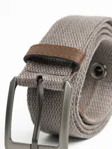 Cinturón de lona color verde militar con hebilla de metal plateado y ojales metálicos.