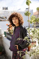 Chaqueta capitoneada con estampado exclusivo en tonos negro, violeta y verde. Tiene cuello redondo, mangas largas con puños elásticos y bolsillos laterales. Edición limitada hecha artesanalmente en Uruguay.