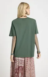 Remera de algodón color verde con estampado frontal estilo western, cuello redondo y mangas cortas. Incorpora mangas largas ajustadas de tul integradas debajo de las mangas cortas.