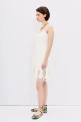 Vestido blanco de algodón con tirantes finos, escote con detalles fruncidos y bordados calados en el ruedo.