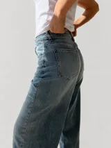 Pantalón de jean con corte wide leg y tiro medio-alto. Presenta un lavado gris azulado desgastado con acabado vintage y ruedo desflecado.
