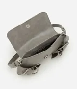 Cartera tipo baguette de tamaño pequeño, confeccionada en poliuretano con acabado estructurado. Presenta una solapa frontal con detalles de hebillas decorativas metálicas, correa para el hombro y un compartimento interior forrado.