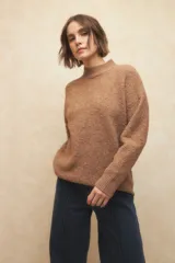 Polera beige de tejido de punto con cuello alto y mangas largas.