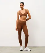 Legging deportiva de tiro alto confeccionada en microfibra elástica, con diseño ajustado y estribos en los pies. Presenta un acabado liso y una estructura que brinda soporte y libertad de movimiento.