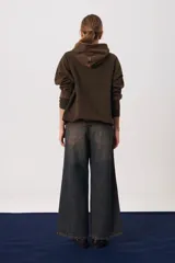 Buzo tipo hoodie de corte oversize y silueta amplia, con capucha, mangas largas y bolsillo frontal tipo canguro. Presenta un acabado desgastado en color marrón habano con terminaciones en rib.