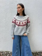 Sweater de punto con diseño nórdico en el canesú, de cuello redondo y manga larga. Presenta una combinación de colores gris, crudo y bordó con textura suave.