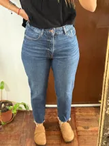 Jean de corte mom fit, tiro alto, color azul clásico con efecto deslavado y dobladillo desmechado en los tobillos.