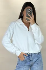 Buzo deportivo color blanco con cuello polo y cierre frontal parcial. Presenta mangas largas con puños elásticos y ruedo ajustable con cordón elástico.
