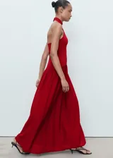 Vestido largo rojo de punto combinado, con cuello halter, sin mangas y diseño evasé con falda fluida y amplia.