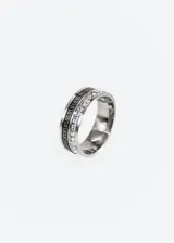 Anillo de acero quirúrgico plateado con una banda central de zirconias y una banda con diseño de guarda griega.