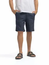 Bermuda de lino color azul marino, de corte recto y largo a la rodilla. Presenta bolsillos laterales y cierre frontal.