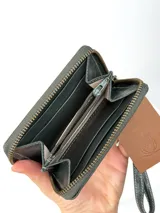 Mini billetera de cuero con textura efecto cocodrilo y cierre perimetral. Presenta un parche central con el logo de la marca grabado.