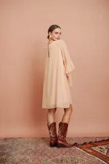 Vestido corto de manga larga acampanada con volados en cascada, color salmón claro, de corte suelto y escote redondo.