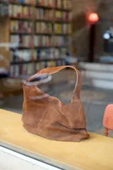 Cartera tipo tote de tamaño mediano, confeccionada en cuero agamuzado. Presenta un diseño simple y amplio con una sola asa integrada y bolsillo interior.