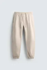 Pantalón estilo jogger de corte slim fit, confeccionado en tejido de algodón con elasticidad. Presenta cintura elástica con cordón ajustable, bolsillos frontales, bolsillos traseros de vivo y bajos con puños elásticos.