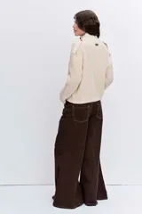 Cardigan de punto acanalado en color bordó, con cuello polo y cierre frontal de botones. Presenta un diseño de hombros caídos y mangas largas con puños ajustados.