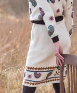 Falda midi de tejido de punto color blanco marfil, confeccionada en lana merino, con diseño bordado a mano de motivos paisley y guardas geométricas en tonos marrones y celestes. Cuenta con cintura elástica.