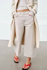 Jeans de tiro medio con diseño culotte y pierna ancha. Cuenta con cintura con trabillas, cierre frontal con cremallera y botón, y cinco bolsillos clásicos.