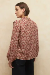 Camisa de manga larga con estampado geométrico en tonos azul y blanco, escote en V con detalle de volado en el cuello, cierre frontal con botones a tono y puños elásticos.