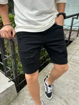 Bermuda de jean negro con corte skinny, presenta roturas desgastadas en la parte frontal y cierre con botón y cremallera.