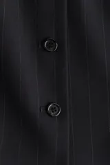 Chaleco largo negro con rayas finas, cuello redondo y cierre frontal de botones. Diseño entallado con bolsillos delanteros ribeteados y abertura en la parte trasera.