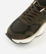 Championes deportivos de diseño urbano, confeccionados en una combinación de poliuretano y poliéster con acabado tipo gamuza. Presentan una silueta con recortes superpuestos, cierre de cordones, entresuela volumosa en tono crema y suela de goma.