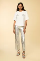 Remera blanca de corte holgado con mangas cortas acampanadas, cuello redondo y apliques de strass con forma de conchas en el frente.