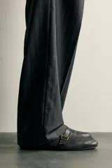 Mocasines de piel color negro, con punta redonda, suela ultrafina y detalle de tira con hebilla metálica dorada en el empeine.