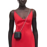 Mini bolso Vanity Marc Jacobs negro con forma cúbica, cierre de cremallera bidireccional, logo frontal en relieve y correa de cadena plateada.