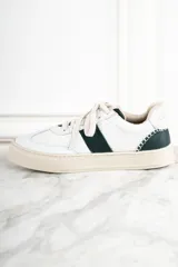 Zapatillas urbanas de cuero blanco con una franja lateral verde oscuro y suela color crema.