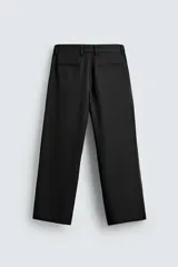 Pantalón de vestir gris oscuro, corte ancho (flare fit) y tiro alto, con bolsillos laterales y falsos bolsillos de vivo en la parte trasera. Presenta un cierre frontal con cremallera y gancho oculto, y botones a presión ocultos en el bajo.