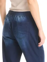 Pantalón tipo jogger de denim azul con efecto lavado. Presenta cintura elástica con cordón ajustable, bolsillos laterales y traseros, y puños elásticos en los tobillos.